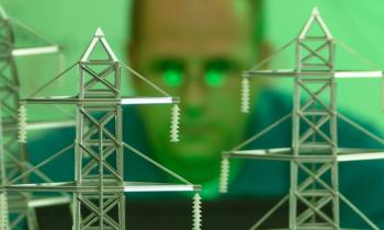 Power lines in the foreground. A man in the background looks at the powerlines.