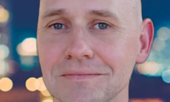 Photo of Orrin Thomas, a man with no hair and blue eyes