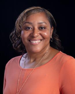 A profile picture of an African American women with a coral top from waist up