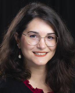 A woman wearing glasses in front of a black background