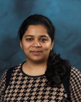 Person smiling in black checker top , Blue background