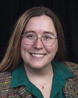A professional headshot of Karlyn Harrod with a black background.