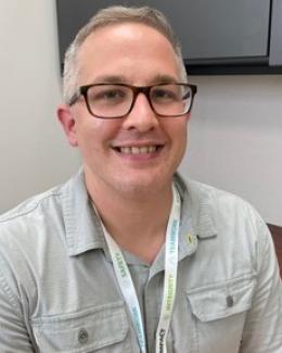 Photo of James Beare smiling. He is a short, Caucasian man, with graying hair and wears glasses.