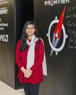 Researcher stand in front of the supercomputer Frontier at Oak Ridge National Laboratory, embodying the convergence of human intellect and cutting-edge technology in the pursuit of scientific breakthroughs.