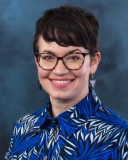 woman with short hair and glasses in a blue shirt