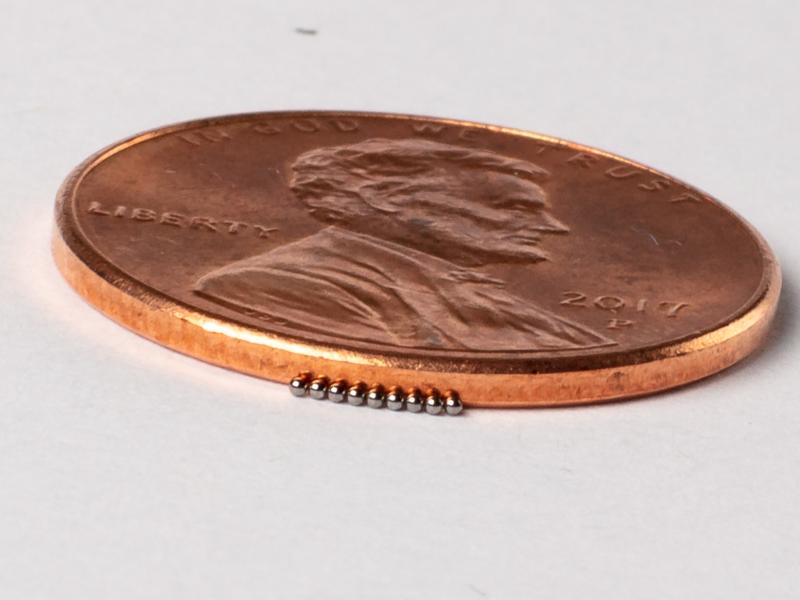 MiniFuel pellets lined up against a penny for size comparison.