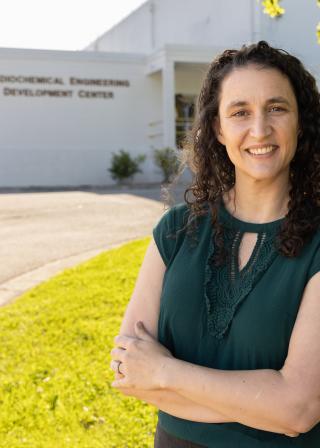 Woman in green shirt stands in front of a white laboratory building