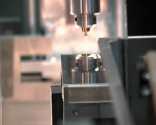Looking along the path toward the sample, the side of the primary neutron mirror appears as a gray band above the secondary mirror. The reflecting surface of the secondary mirror reflects the drill chuck. The sample is on the end of the drill chuck.