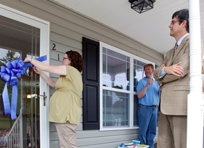 Carly Gilbert cuts the ribbon on her new home in Oak Ridge, constructed for Aid to Distressed Families of Appalachian Counties by volunteers from Oak Ridge National Laboratory's Team UT-Battelle. Looking on are Lab Director Thom Mason, right, and ADFAC board member Darrell Daugherty, center.