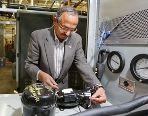 ORNL's Pradeep Bansal examines an Embraco linear compressor, which will be used in a Whirlpool-ORNL project aimed at building a more energy-efficient refrigerator.