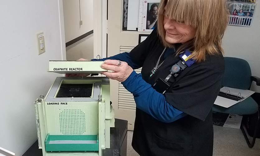 Deb Austin lifts the top of the model to reveal the control rods inside.