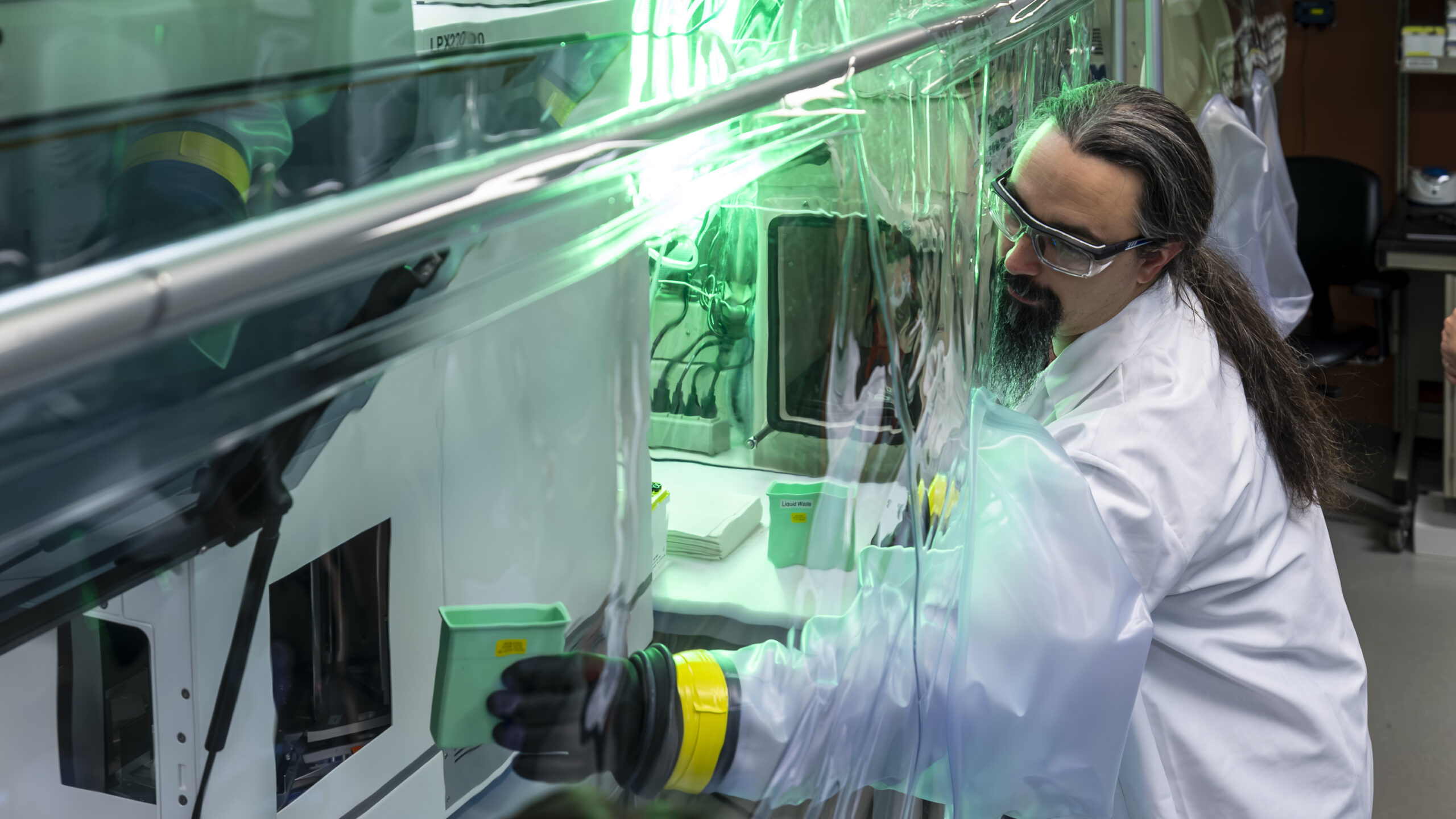 Researcher working in glove phenotyping lab glove box in green lighting