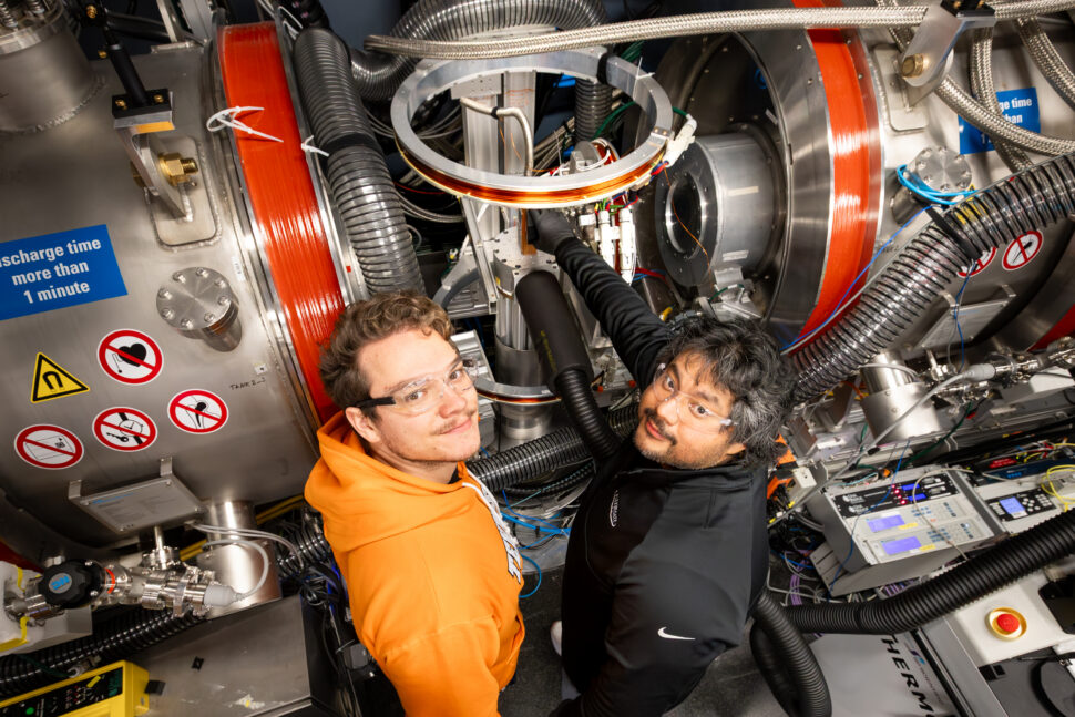 University of Windsor doctoral candidates Stuart Castillo and Maks Dziura stand beside the sample mount of the Neutron Spin Echo instrument (BL-15) at Oak Ridge National Laboratory’s Spallation Neutron Source. Their research uses neutron scattering to probe nanoscale dynamics in advanced materials, supporting scientific innovation that strengthens U.S. energy, manufacturing, and security capabilities.