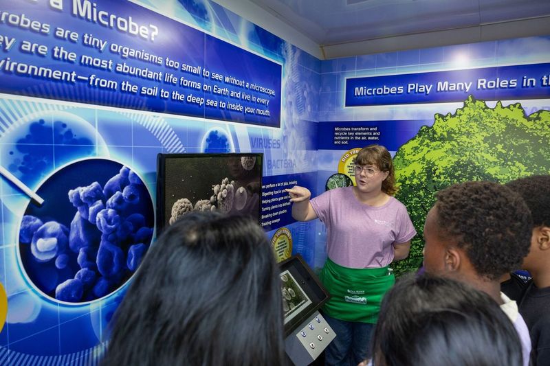 Jenny Warnock is talking to a group of students about microbes during the Traveling Science Fair