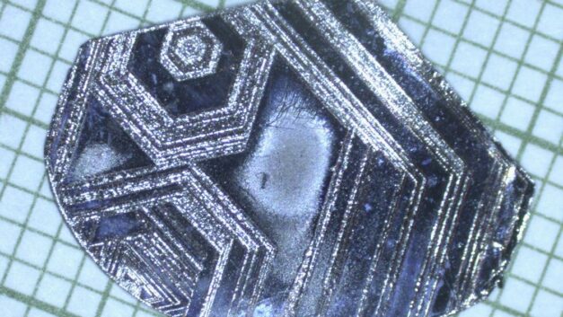 A misshapen piece of metal with geometric marks