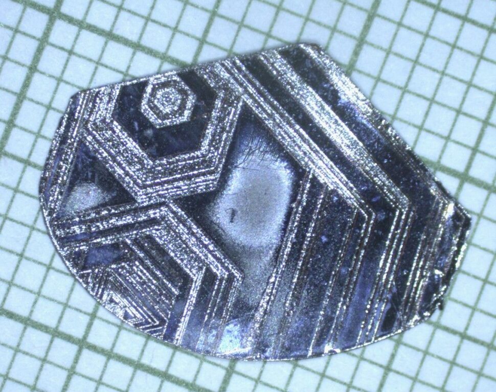 A misshapen piece of metal with geometric marks