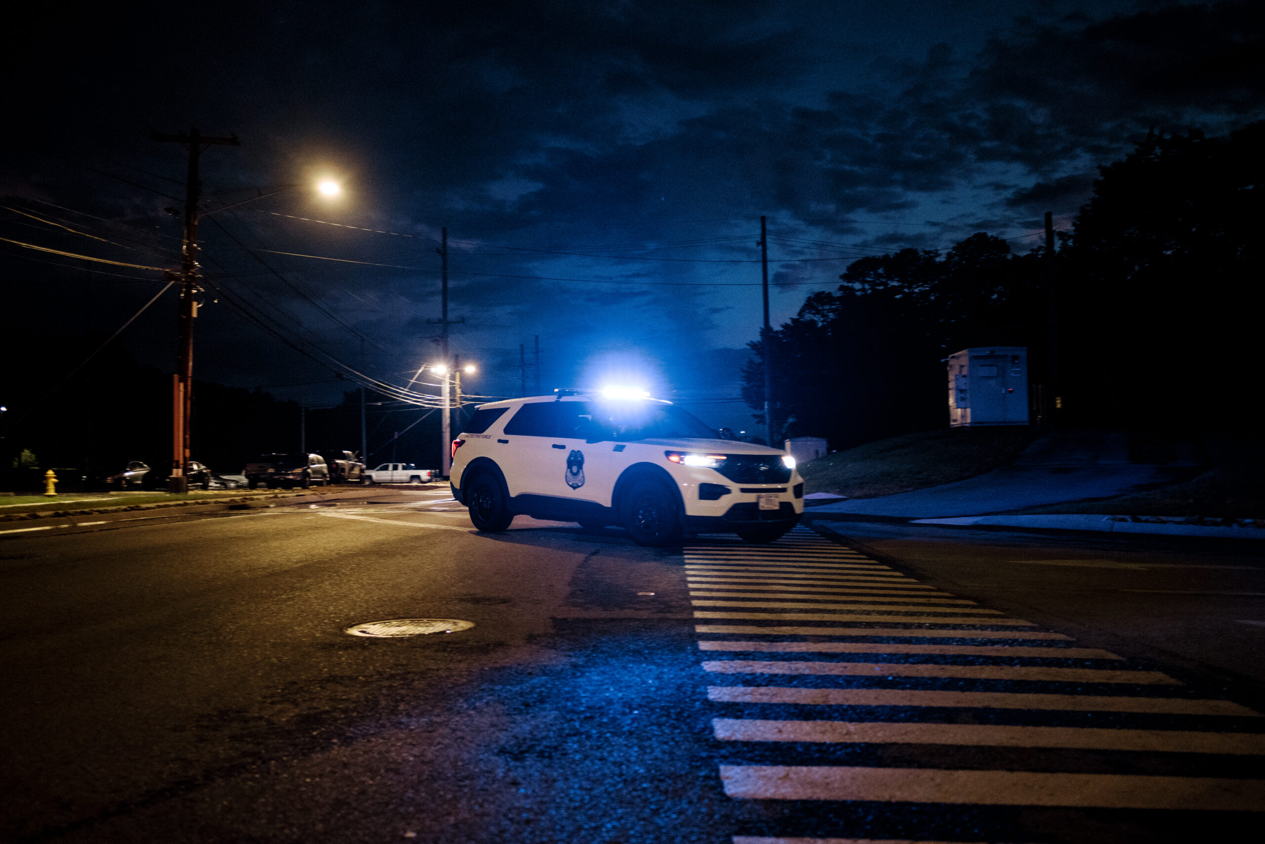 Security vehicle with flashing lights blocks an intersection at night on the ORNL campus.