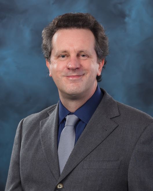 Biosecurity programs lead, David Graham is wearing a grey suit, posing for photo with blue background