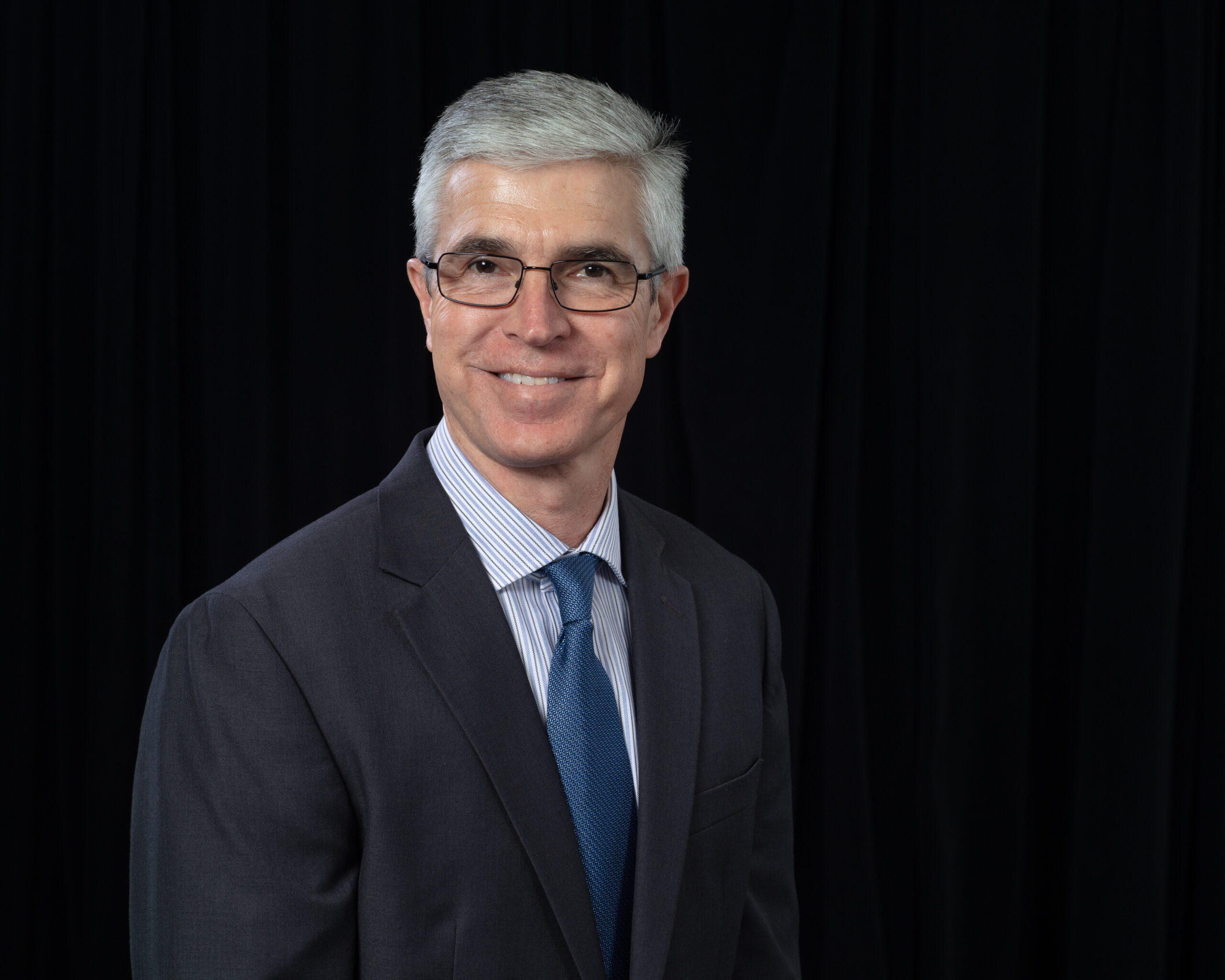 ORNL partnerships director Shaun Gleason is posing in a suit for a photo with a black background