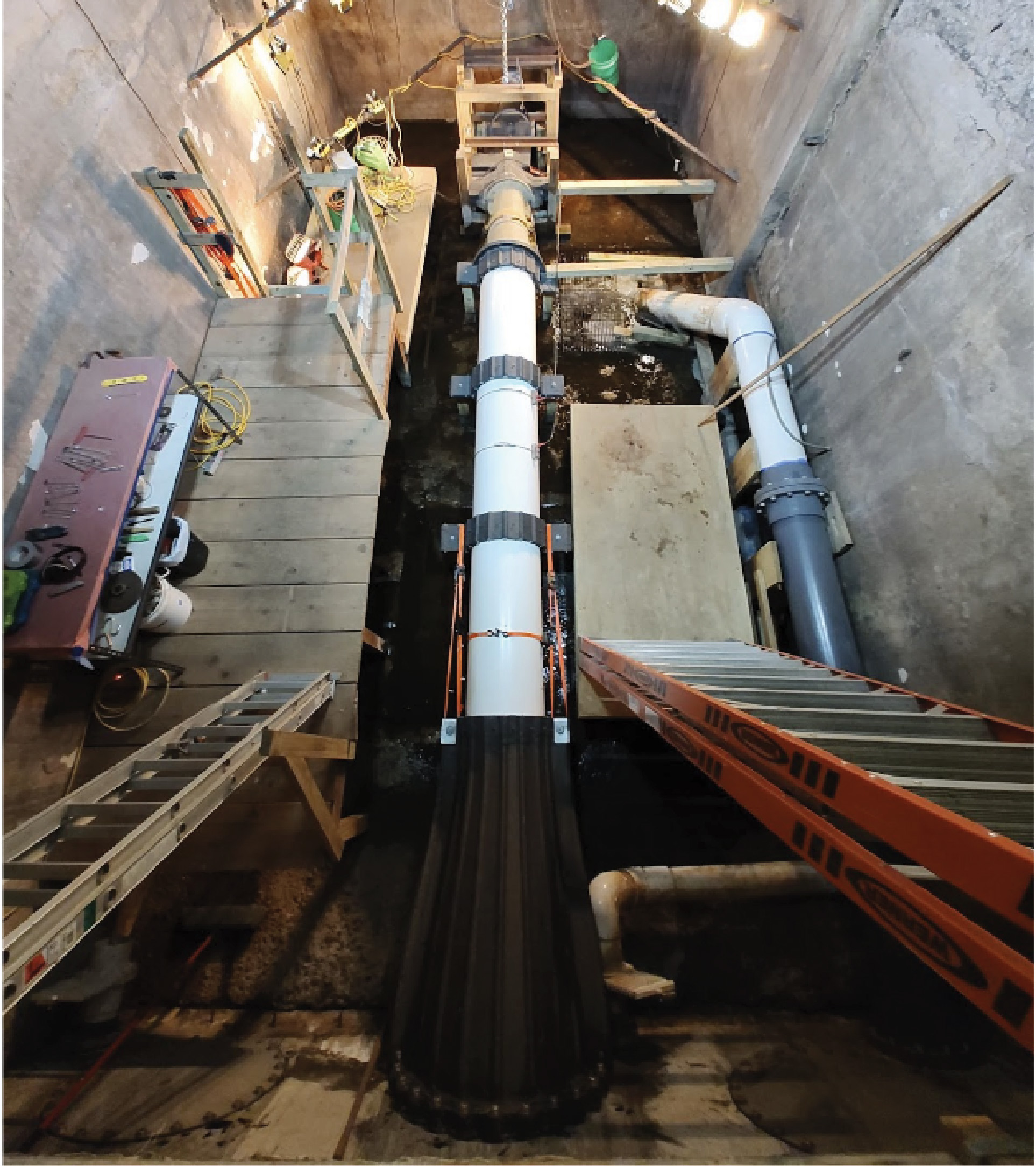 The 30-foot-long testbed sits inside Cadens’ test facility. Multiple  3D-printed parts are shown, including the intake adapter, runner, and end cap flanges.