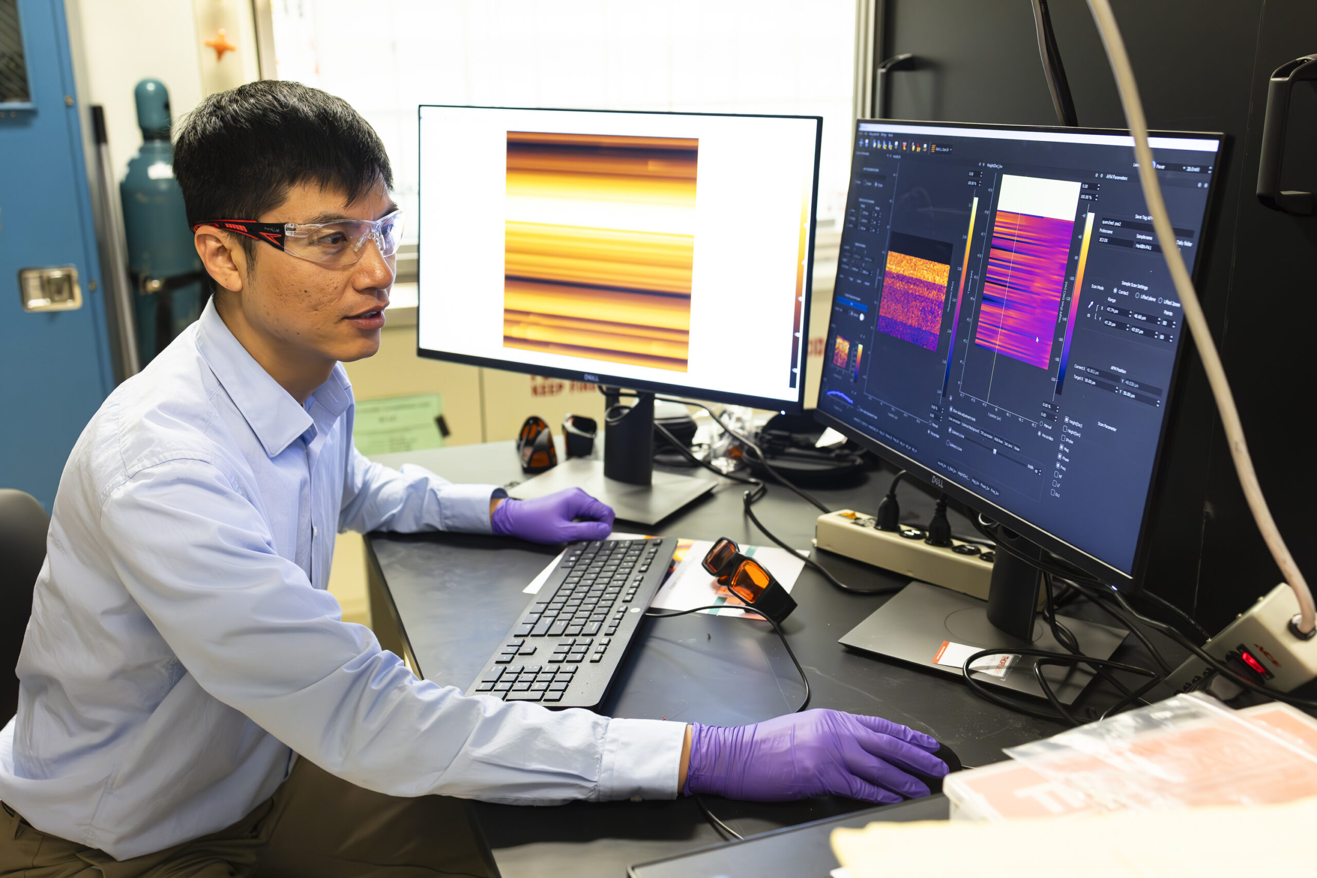 Scientists is sitting to the left, working on computer in the lab