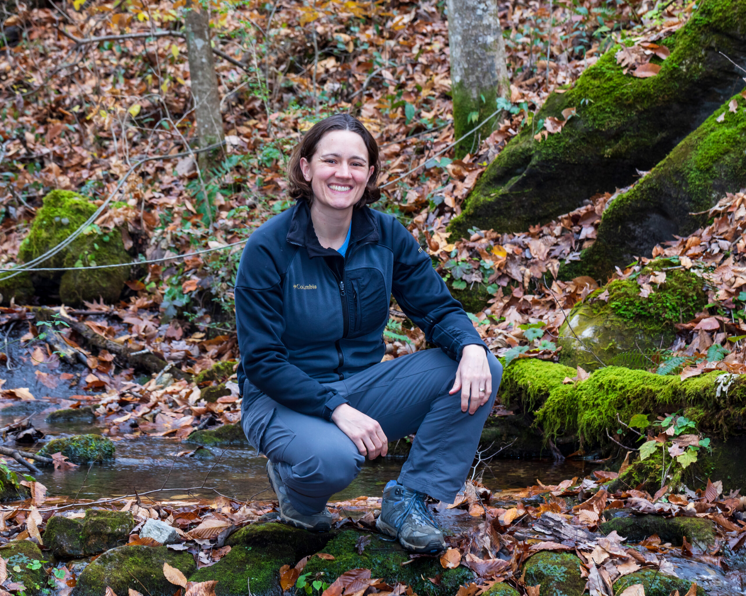 ORNL researcher Natalie Griffiths by a forest stream in the fall