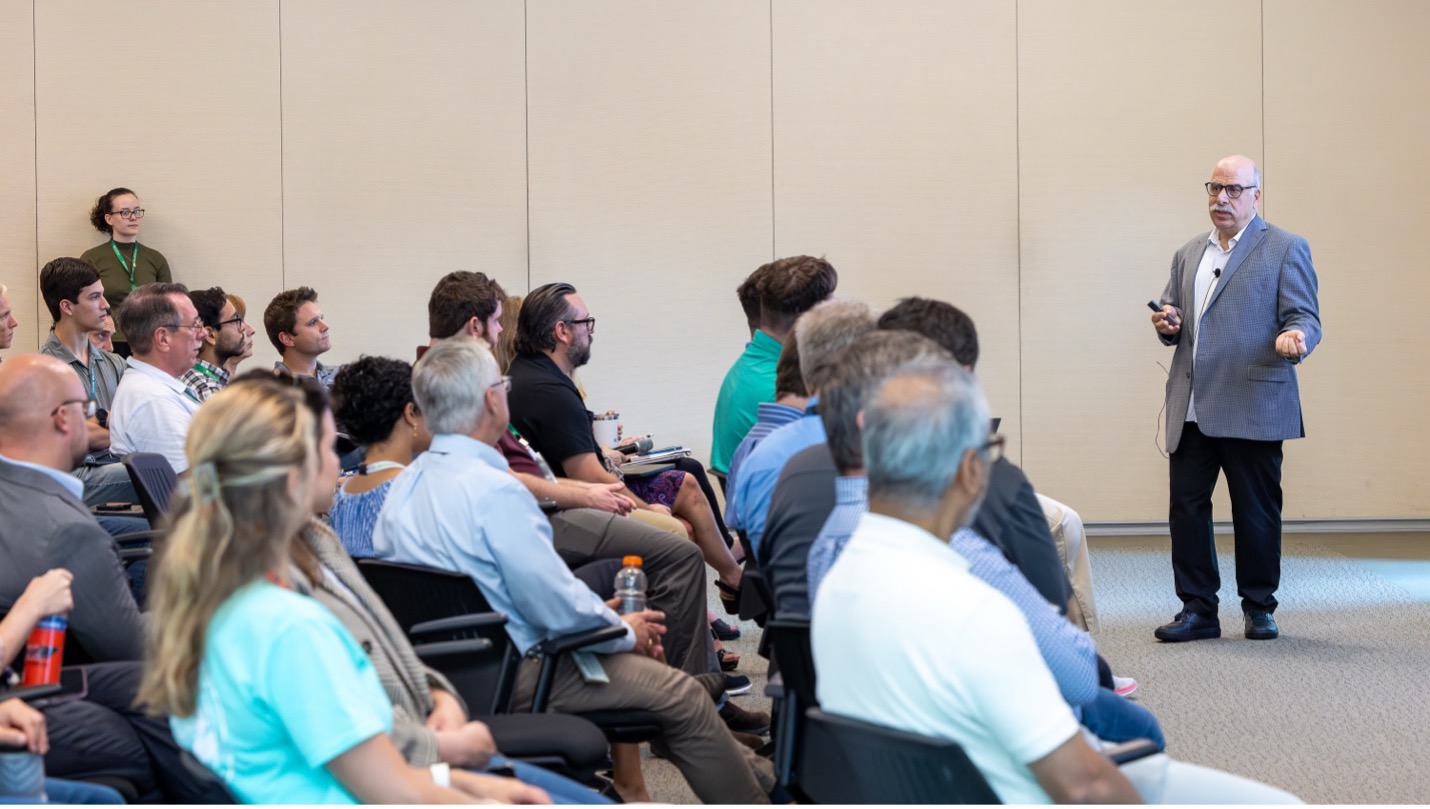 Man addresses a crowd in a conference room