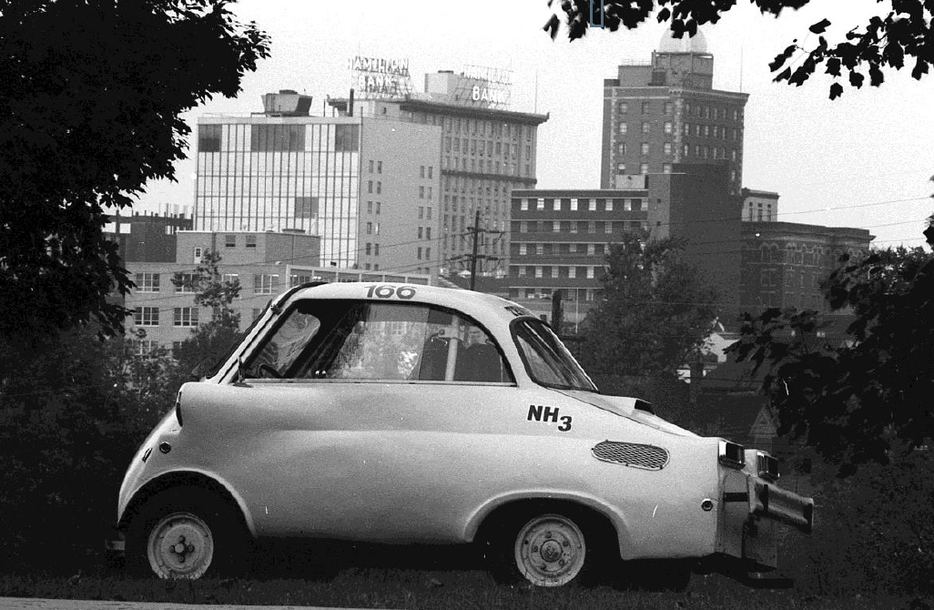 Black and white photo of small vehicle in the city 