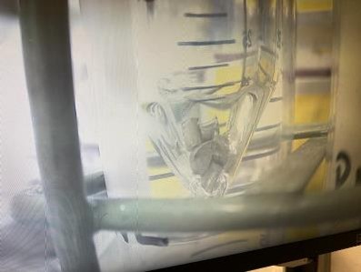 Glass container holding small metal capsules submerged in liquid