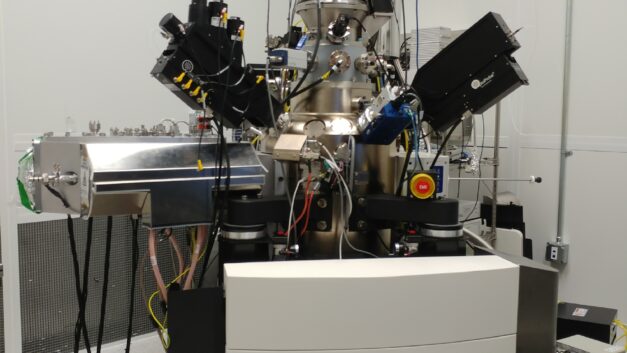 A large grey base supports a complex black machine with protrusions