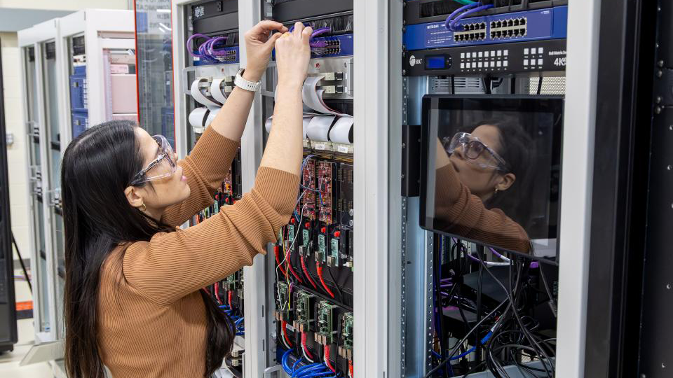 Renata Rezende da Costa Reis Kimpara of Grid Systems Architecture Group reconnects network cables inside a control rack in the Grid-C Hardware-in-the-Loop Protection Lab at Oak Ridge National Laboratory.