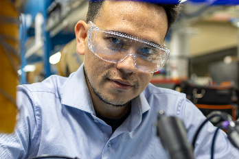 A GRID-C researcher looks directly at the camera, wearing safety goggles.