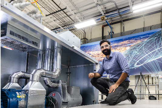 A researcher kneels near equipment in the Grid Research Innovation and Development Center.
