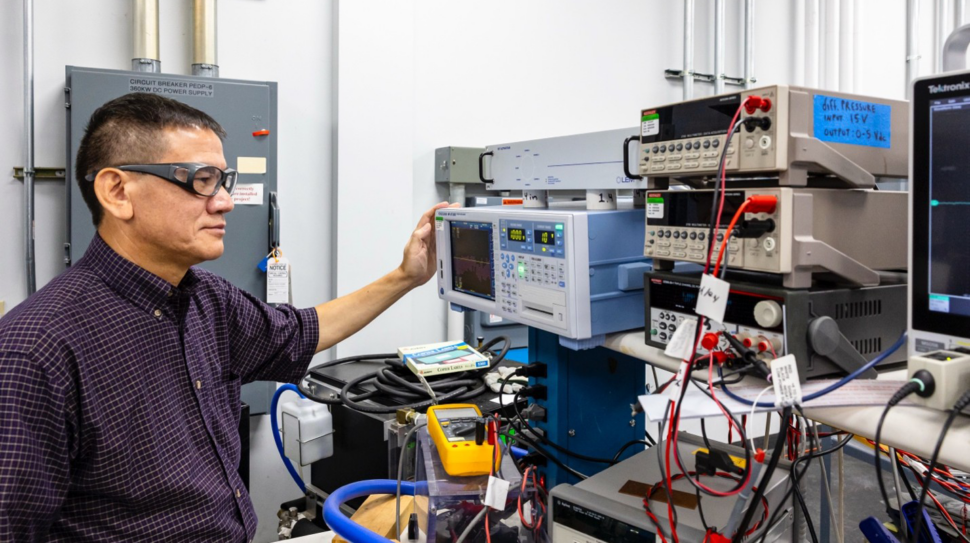 A scientist in safety goggles engages in vehicle power electronics research.