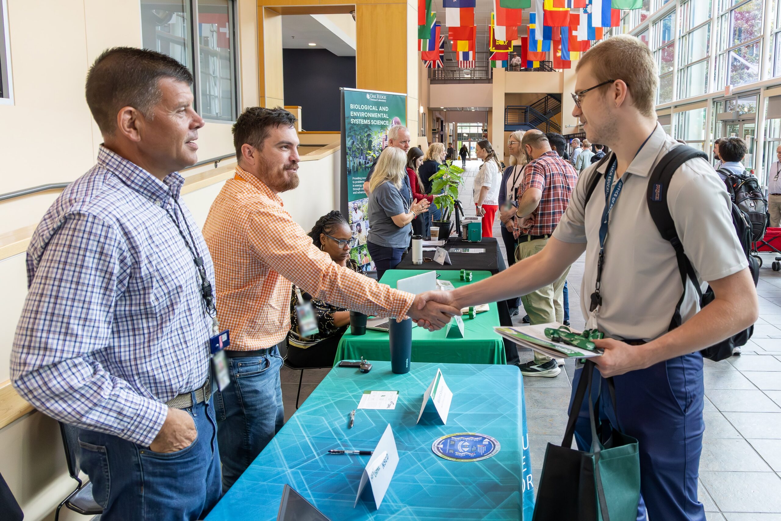 Michael Hurst, center left, administrative assistant and education coordinator at Oak Ridge National Laboratory, shakes hands with a summer intern during an intern mentor meetup at ORNL.