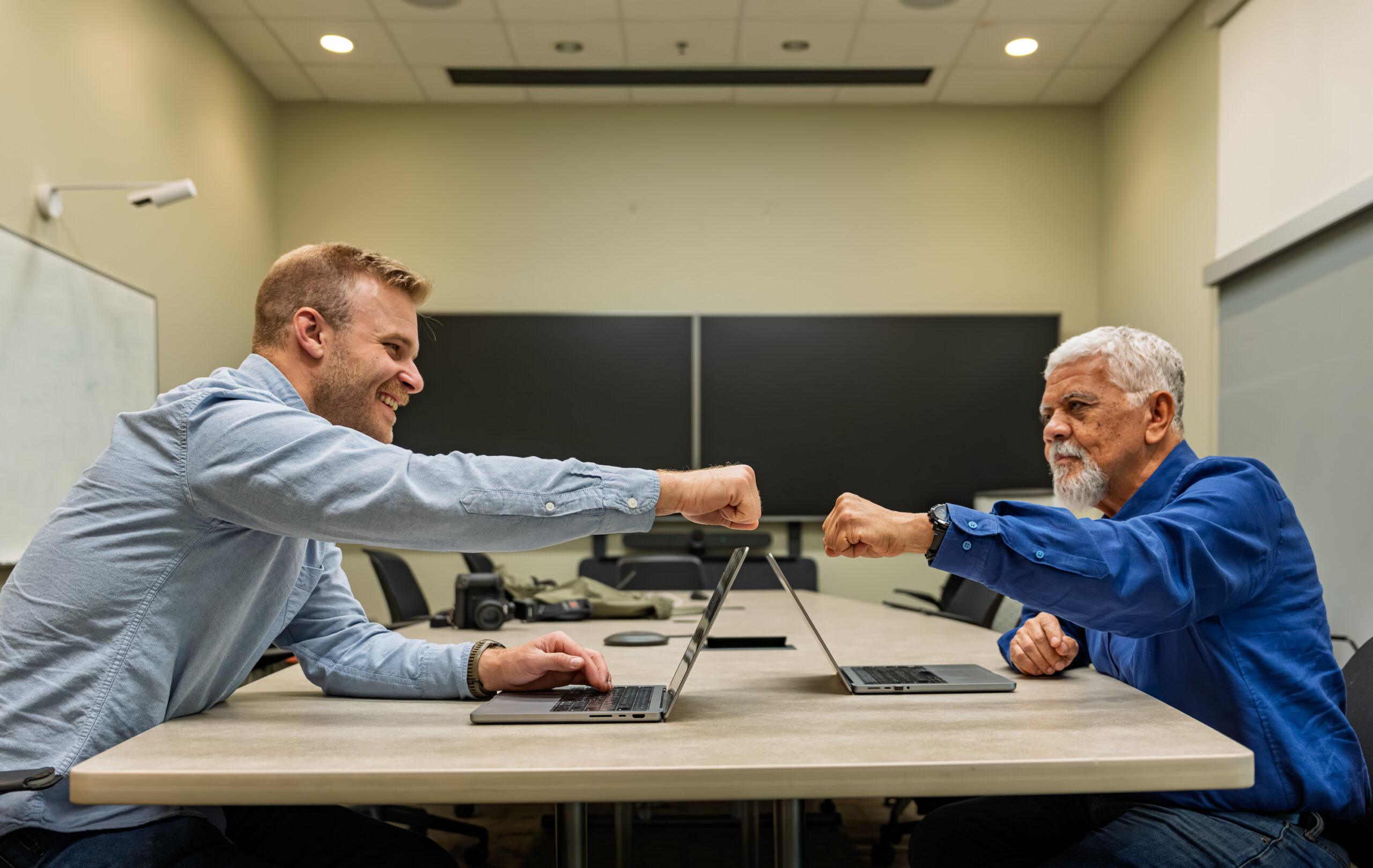 Luiz Leal and Jesse Brown stand in a conference room at Oak Ridge National Laboratory with research data displayed on two monitors behind them.
