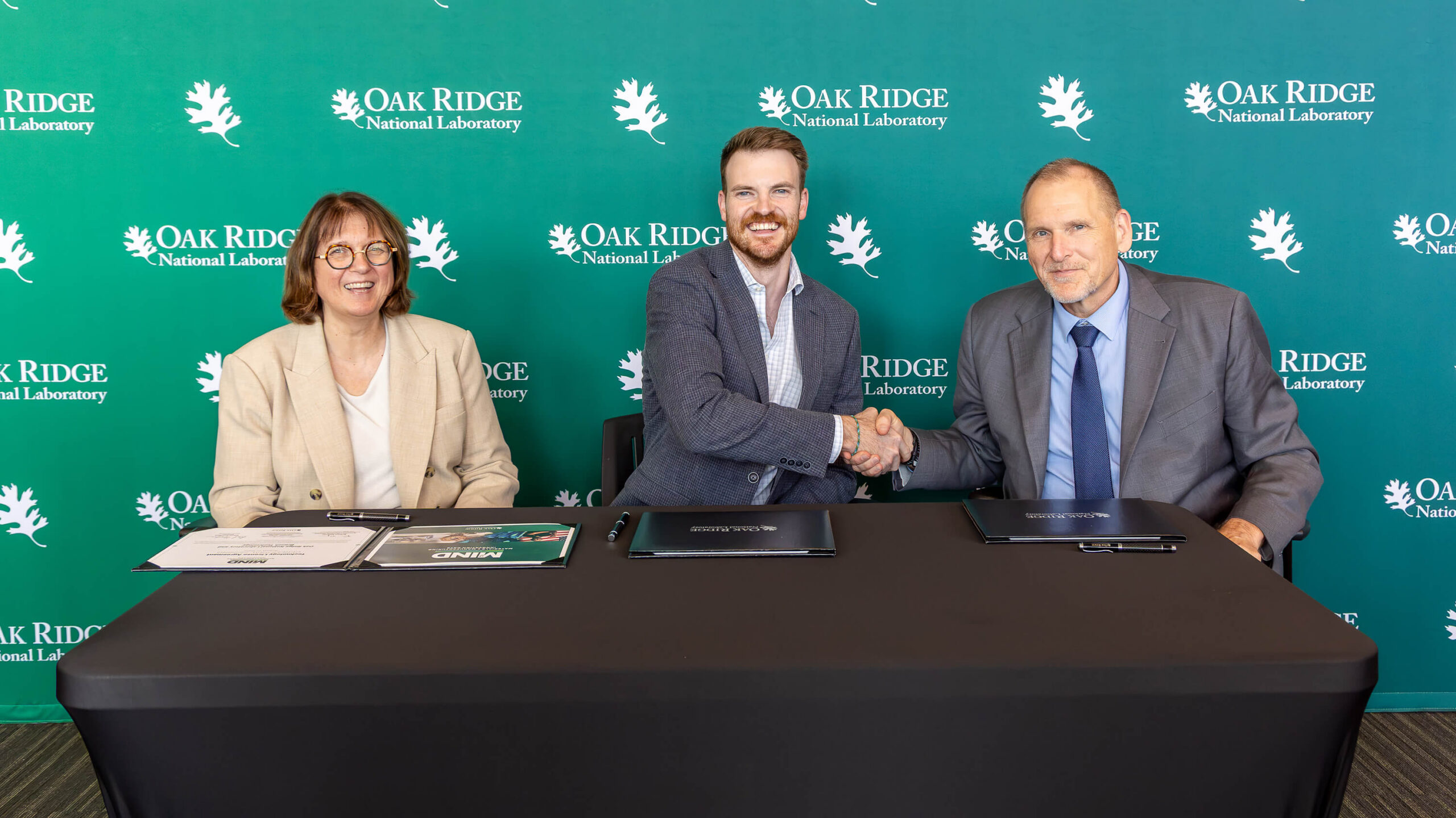 Cynthia Jenks, associate laboratory director for the Physical Sciences Directorate at Oak Ridge National Laboratory, left; David Goodloe, director of Branch Technology’s Branch Regenerate business unit, center; and Robert Wagner, ORNL associate laboratory director for the Energy Science and Technology Directorate, sign a licensing agreement Wednesday, Aug. 19, 2026, during Materials and Manufacturing Innovation Days, or M2IND, at ORNL. 
