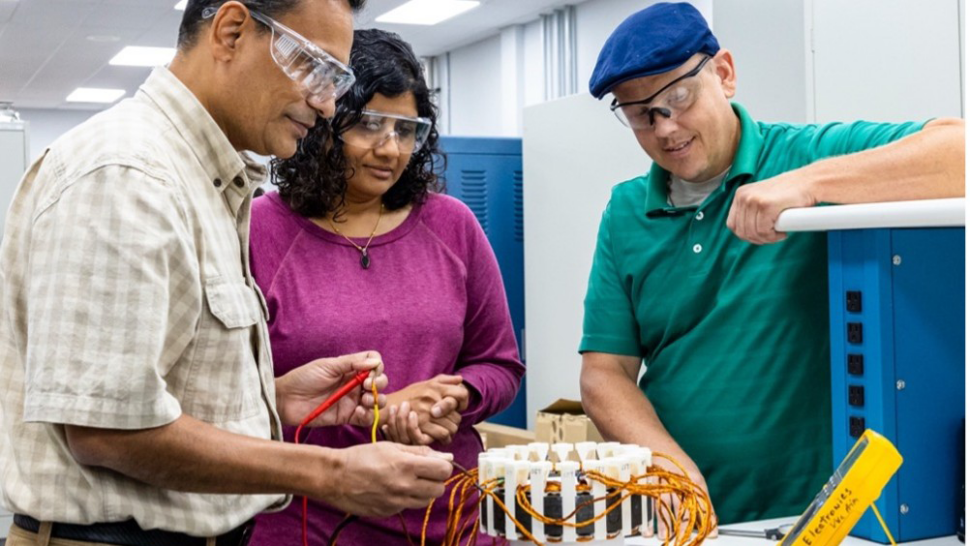 ORNL researchers Praveen Kumar, left, Vandana Rallabandi, center, and Jon Wilkins, right, examine a stator, a key component of electric motors, as part of efforts to improve motor design.