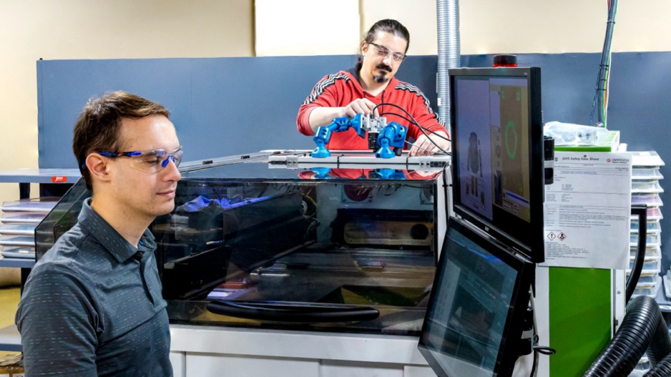 ORNL scientists Luke Scime, foreground, and Vincent Paquit demonstrate the Peregrine software system on a powder-bed 3D printer.