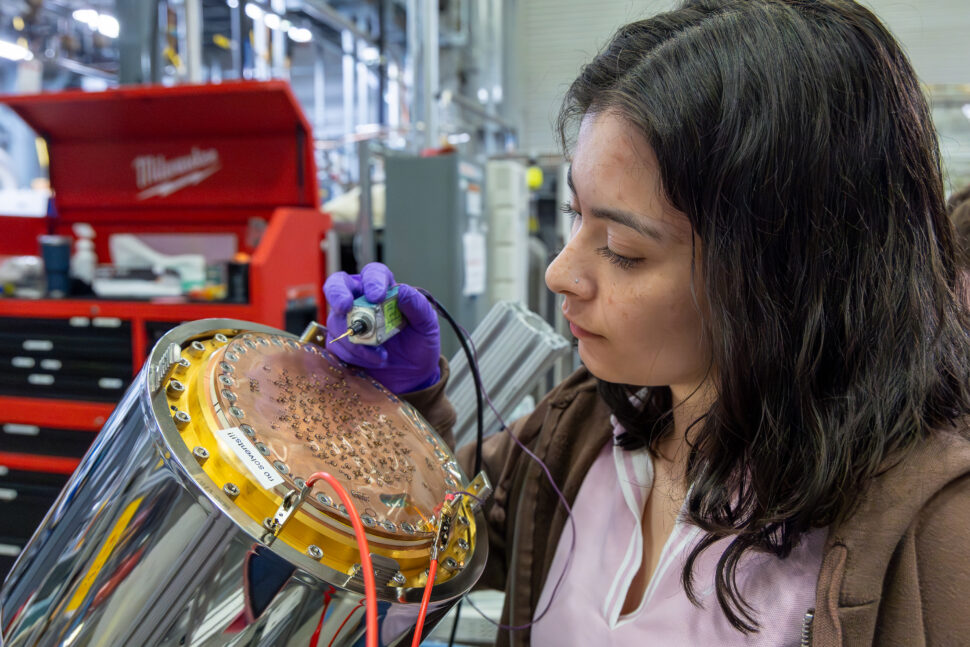 Sarah Estupinan Jimenez uses a probe to test electronics on the Nab detector system at a beamline laboratory inside the Spallation Neutron Source at Oak Ridge National Laboratory.