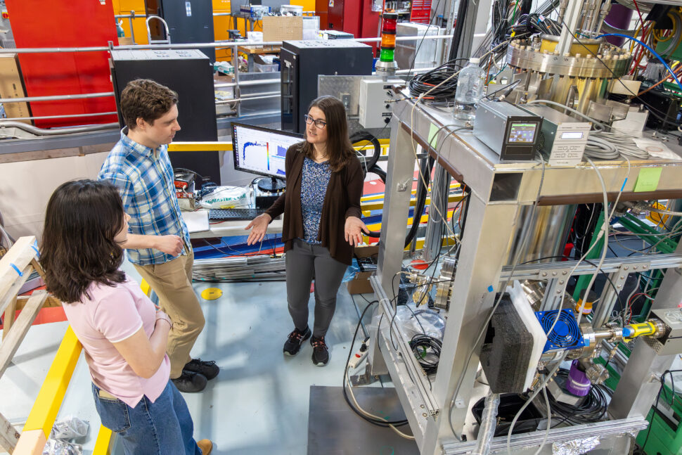 Sarah Estupinan Jimenez, Andrew Hagemeier and Leah Broussard stand beside the Nab experiment apparatus discussing detector data at the Spallation Neutron Source at Oak Ridge National Laboratory.