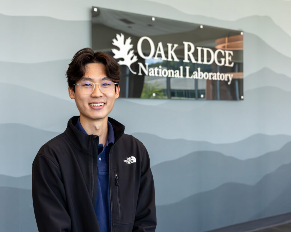 Seokchan Oh smiles for a portrait in front of an Oak Ridge National Laboratory sign during an intern ice cream social on July 16, 2026.