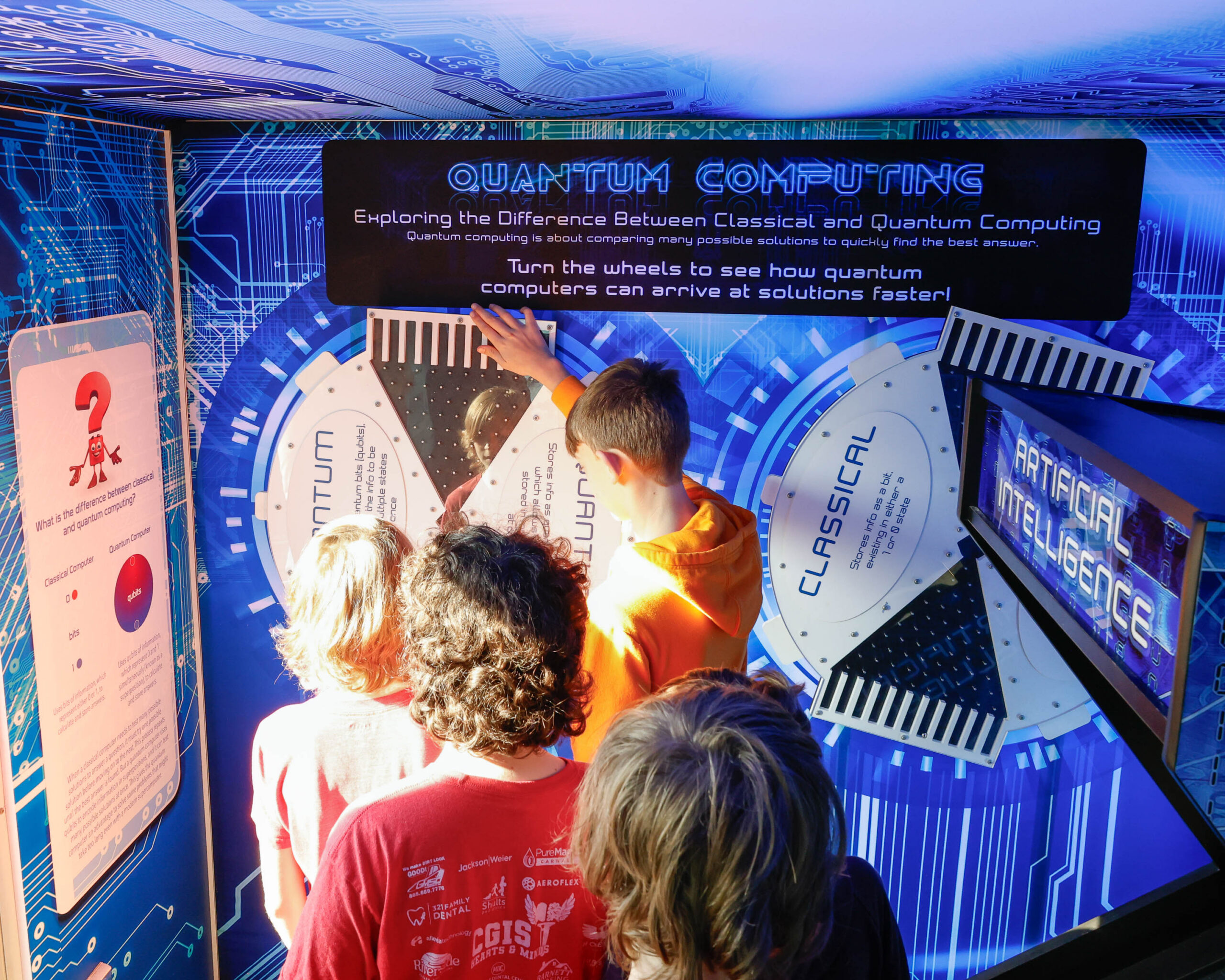 Students turn interactive wheels at a quantum computing exhibit.