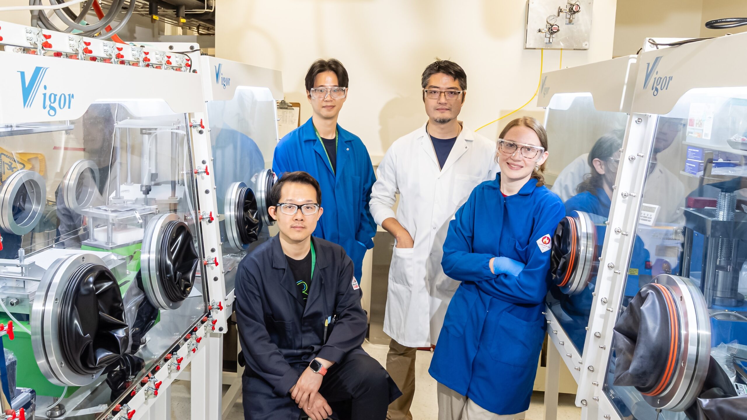 ORNL researchers pose beside gloveboxes in the STAR Lab.
