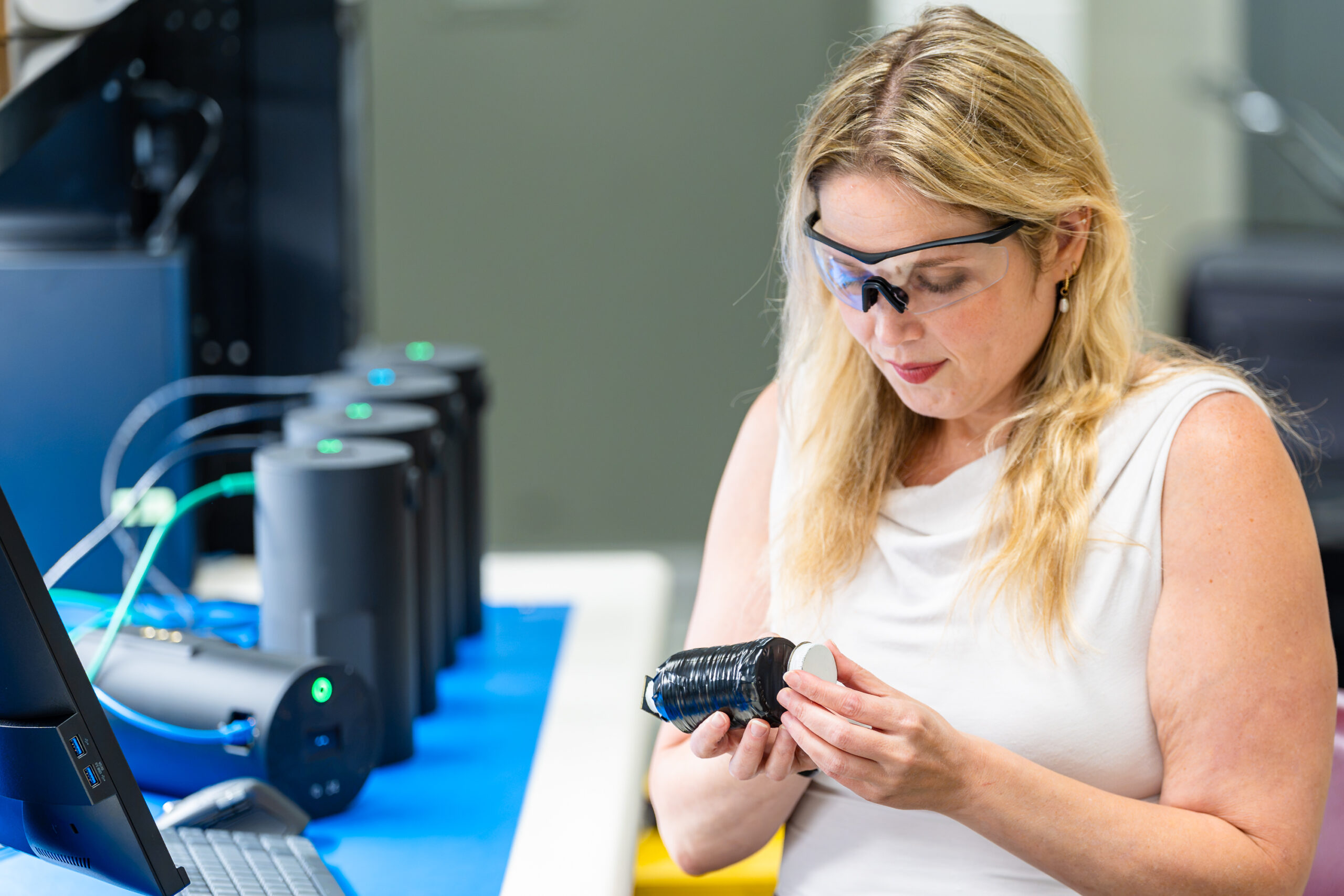 Researcher examines a component beside several monitoring devices.